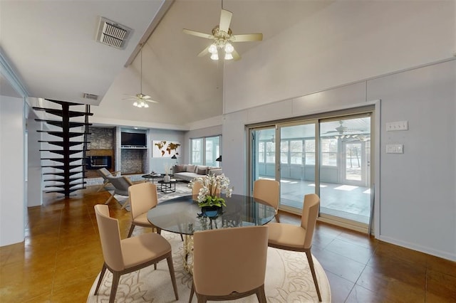 tiled dining room featuring ceiling fan, visible vents, high vaulted ceiling, and a fireplace