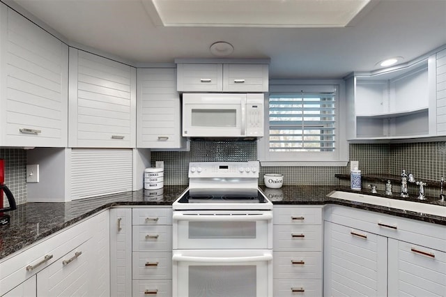 kitchen with tasteful backsplash, a sink, dark stone counters, white appliances, and white cabinetry