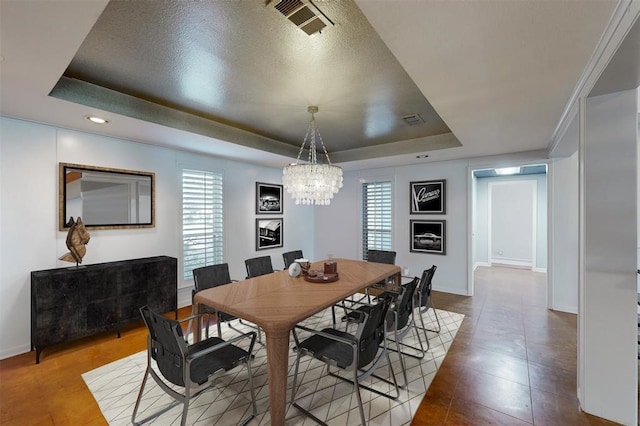 tiled dining room featuring an inviting chandelier, plenty of natural light, a tray ceiling, and visible vents
