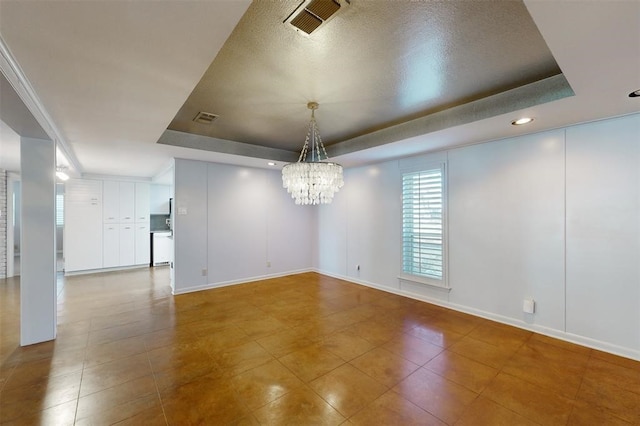 tiled empty room with an inviting chandelier, baseboards, a tray ceiling, and visible vents