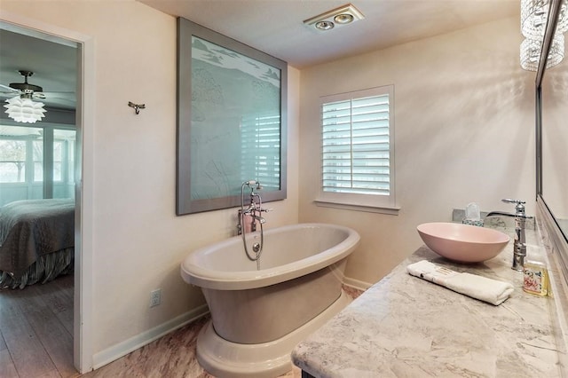 ensuite bathroom featuring connected bathroom, baseboards, a freestanding bath, and ceiling fan