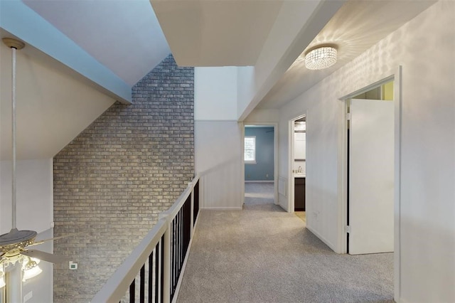 hall with brick wall, light colored carpet, and lofted ceiling