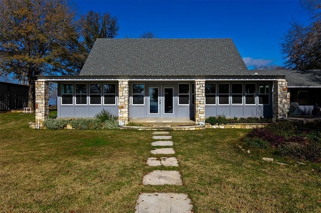view of front facade featuring roof with shingles, a front lawn, stone siding, board and batten siding, and french doors
