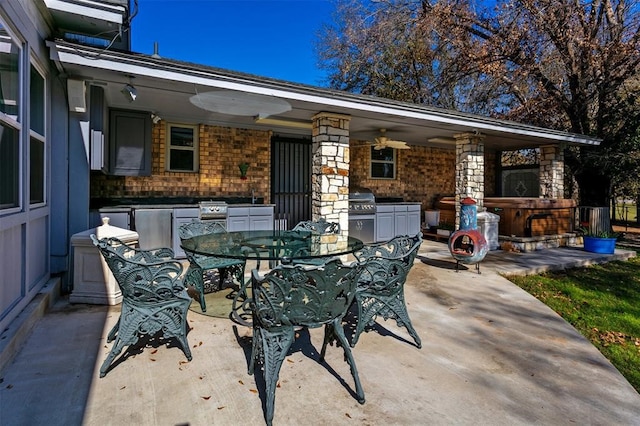 view of patio featuring area for grilling, exterior kitchen, a ceiling fan, and outdoor dining space