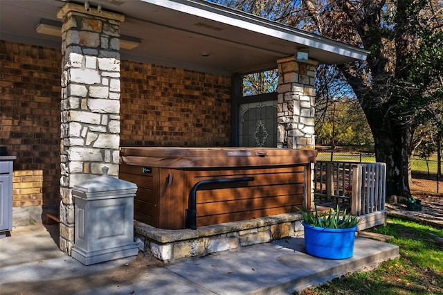 view of patio / terrace with a hot tub and fence