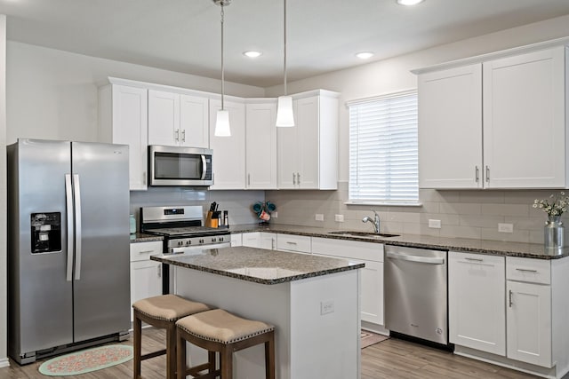kitchen with a kitchen island, a sink, light wood finished floors, stainless steel appliances, and recessed lighting