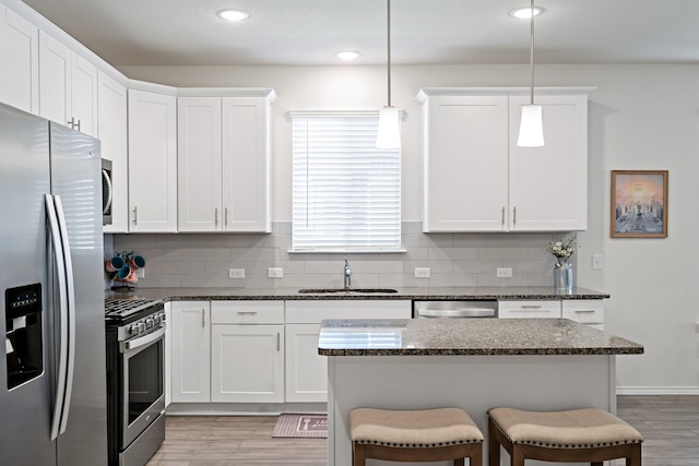 kitchen with a sink, appliances with stainless steel finishes, light wood-style floors, and a breakfast bar