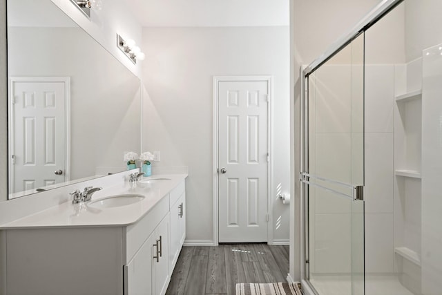 full bathroom with wood finished floors, a sink, baseboards, and a stall shower