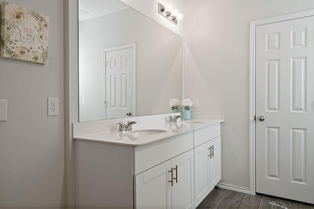 full bathroom featuring double vanity, a sink, baseboards, and wood finished floors
