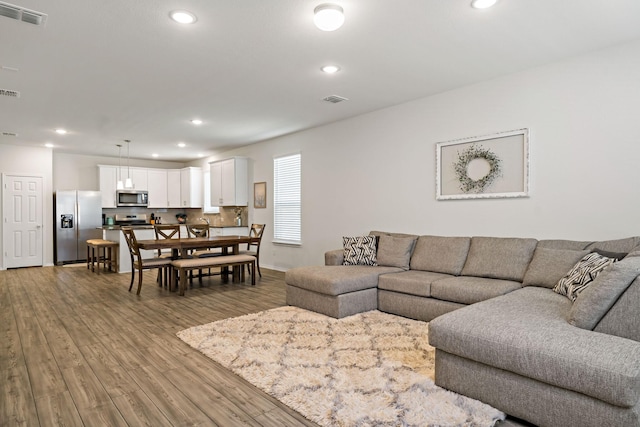 living area featuring recessed lighting, visible vents, and wood finished floors