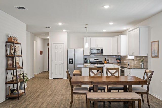 dining room featuring recessed lighting, baseboards, visible vents, and wood finished floors