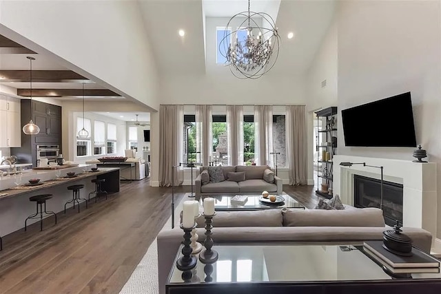 904 Devonshire Dr, Allen, TX 75013 - living room featuring a glass covered fireplace, a towering ceiling, dark wood-style floors, recessed lighting, and a chandelier