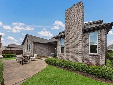 904 Devonshire Dr, Allen, TX 75013 - back of property featuring a chimney, brick siding, fence, a yard, and a patio