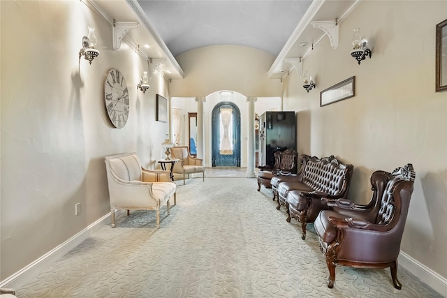 interior space featuring ornate columns, baseboards, and vaulted ceiling