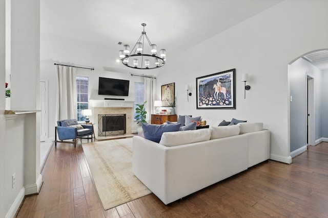 8926 White Pine Ln, Dallas, TX 75238 - living area featuring an inviting chandelier, baseboards, a fireplace with raised hearth, arched walkways, and dark wood finished floors