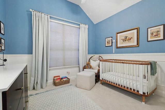 8926 White Pine Ln, Dallas, TX 75238 - carpeted bedroom featuring wainscoting, a nursery area, a ceiling fan, and vaulted ceiling