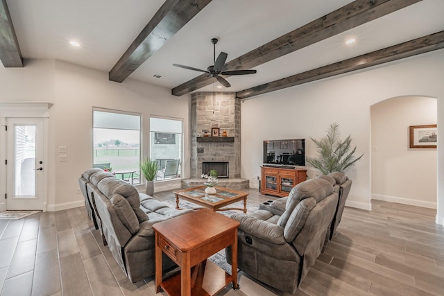 living area featuring arched walkways, ceiling fan, beamed ceiling, and wood finished floors
