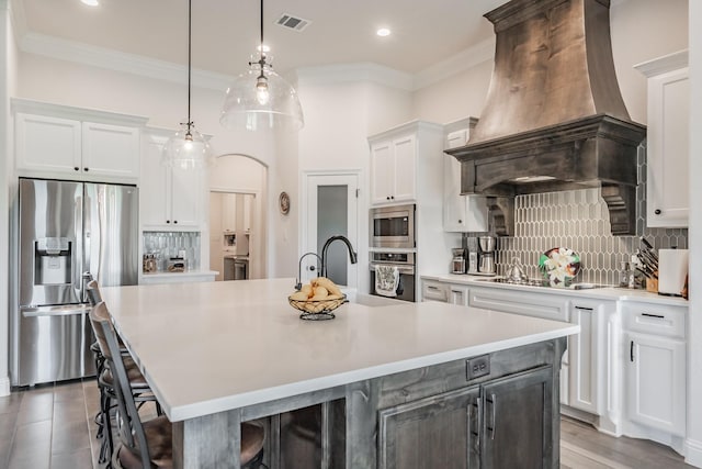kitchen featuring visible vents, decorative backsplash, premium range hood, light countertops, and appliances with stainless steel finishes