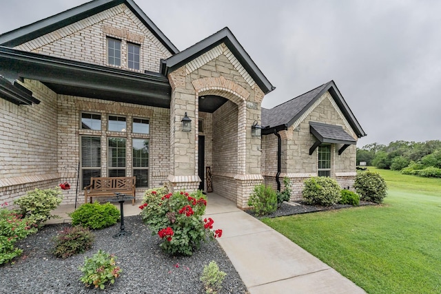 view of front of house with brick siding, a front yard, stone siding, and a porch