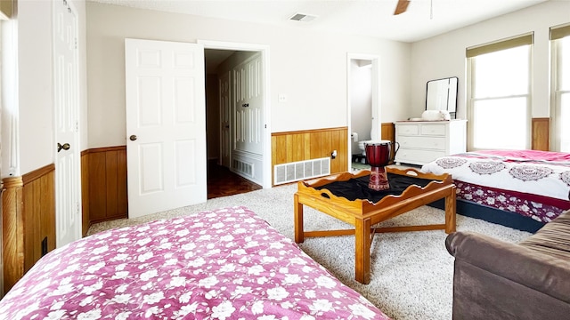 carpeted bedroom featuring visible vents, wainscoting, and wooden walls