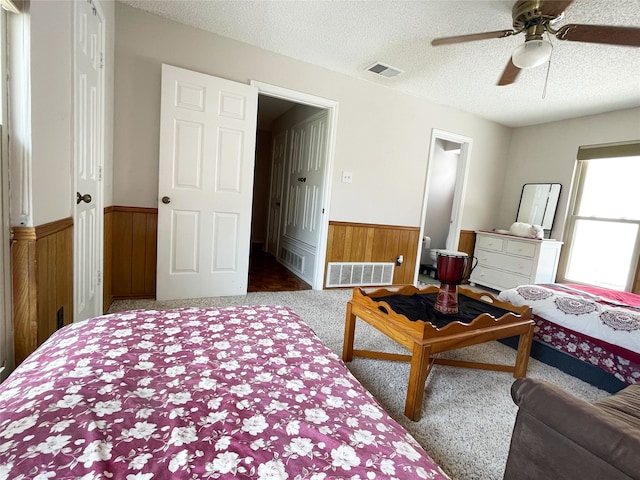 bedroom featuring carpet floors, wood walls, visible vents, and a wainscoted wall