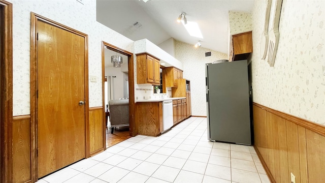 kitchen featuring vaulted ceiling with skylight, a wainscoted wall, freestanding refrigerator, and wallpapered walls