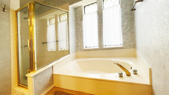 bathroom with a bath, a wealth of natural light, and a shower stall