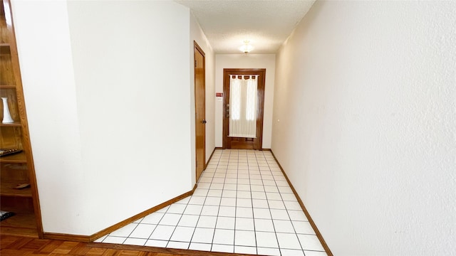 corridor featuring baseboards and a textured ceiling