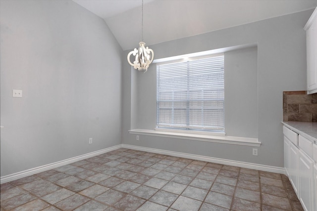 unfurnished dining area with baseboards, vaulted ceiling, stone finish flooring, and a chandelier