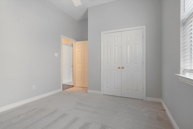 unfurnished bedroom with a ceiling fan, baseboards, light carpet, and a closet