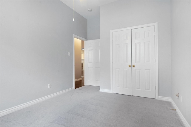 unfurnished bedroom with baseboards, carpet, and a towering ceiling