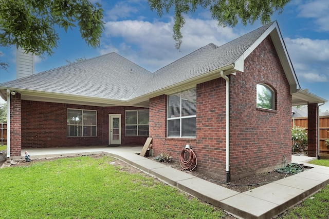 rear view of house with a yard, brick siding, a chimney, and roof with shingles