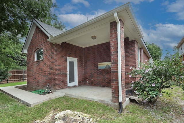 back of property with fence, a patio area, and brick siding