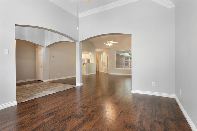 unfurnished living room featuring baseboards, a ceiling fan, arched walkways, and wood finished floors