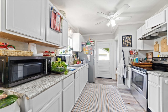 2612 1st St, Brownwood, TX 76801 - kitchen with stainless steel appliances, under cabinet range hood, a sink, ornamental molding, and light wood finished floors