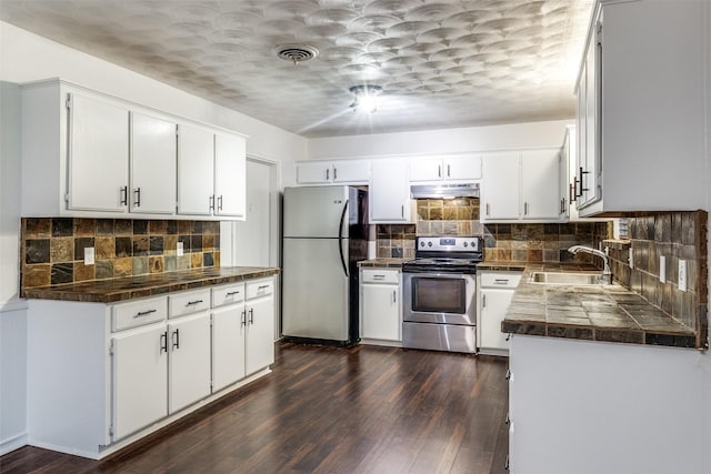 kitchen featuring under cabinet range hood, appliances with stainless steel finishes, a sink, and dark wood finished floors