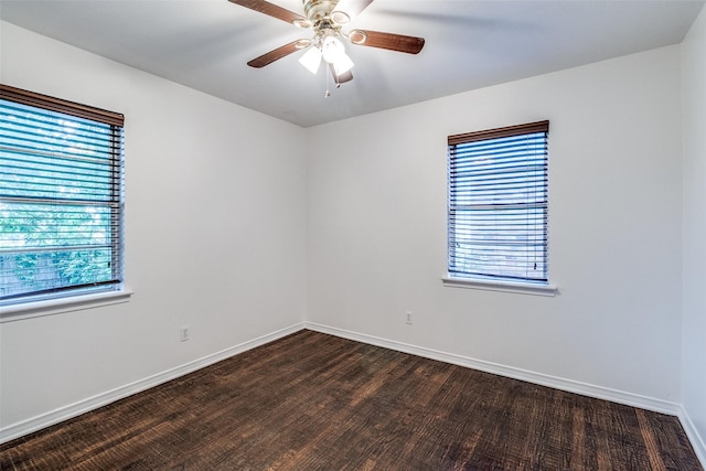 spare room with baseboards, a ceiling fan, and dark wood-style flooring