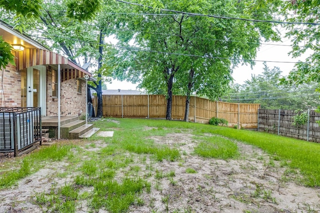view of yard with a fenced backyard and central AC