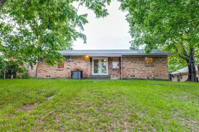 rear view of property featuring brick siding, a lawn, french doors, and entry steps