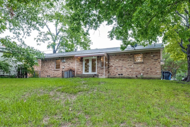back of property with a yard, brick siding, and french doors