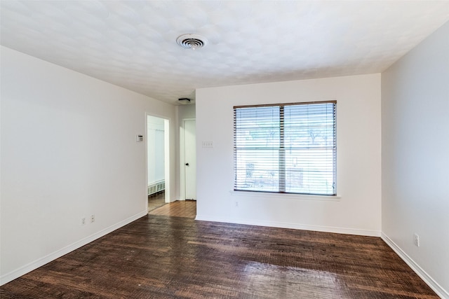 empty room featuring baseboards, visible vents, and wood finished floors
