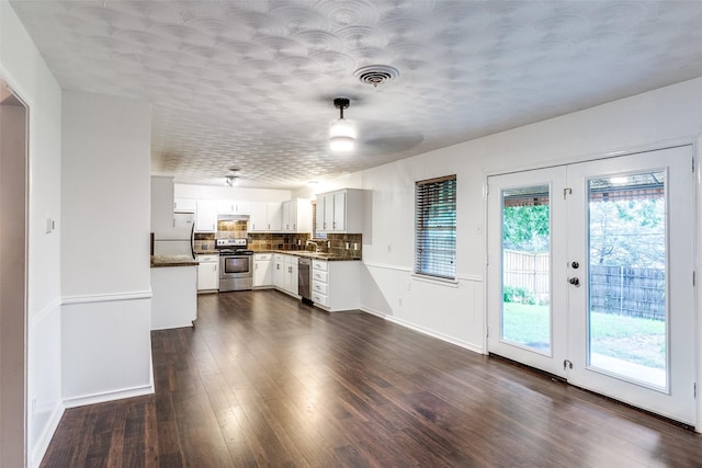 interior space with dark wood-type flooring, appliances with stainless steel finishes, dark countertops, and tasteful backsplash