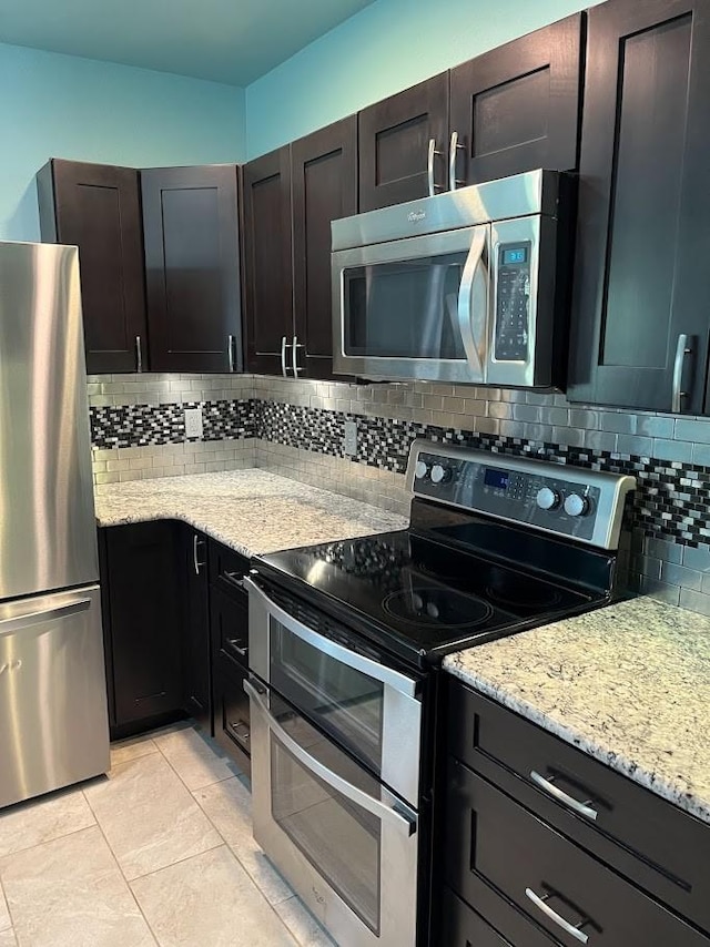 1824 Shady Point Circle Dr, San Angelo, TX 76904 - kitchen featuring light tile patterned floors, light stone counters, backsplash, and stainless steel appliances