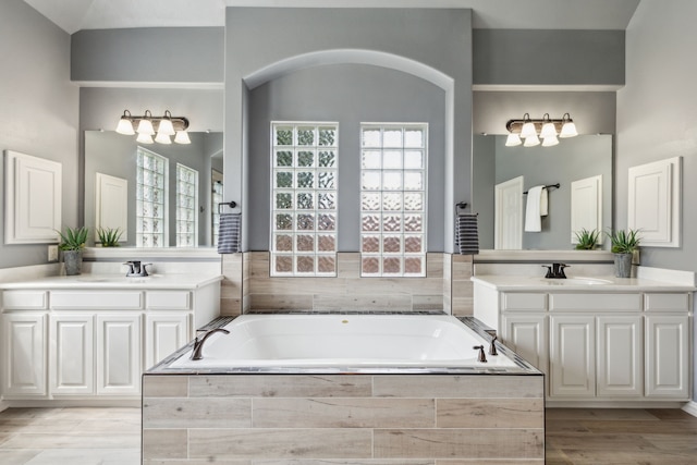 1306 Andrew Ct, Lewisville, TX 75056 - bathroom with a garden tub, two vanities, and wood finished floors