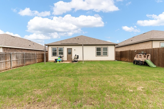 rear view of house featuring a lawn and a fenced backyard