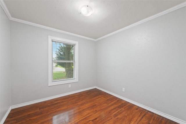 spare room featuring baseboards, ornamental molding, and dark wood-type flooring