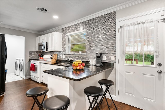 kitchen with white gas stove, visible vents, a sink, stainless steel microwave, and washer and clothes dryer