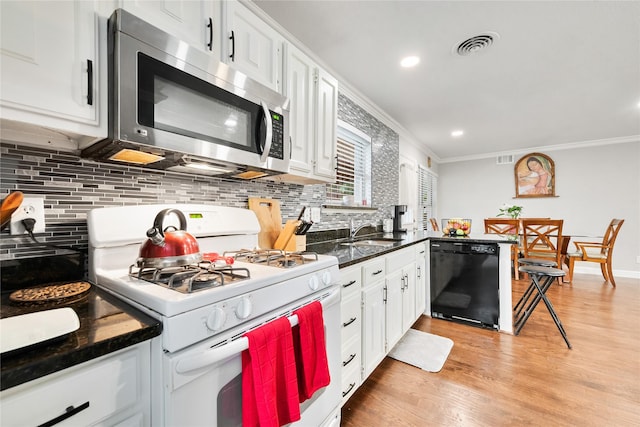 kitchen featuring crown molding, white gas range oven, stainless steel microwave, and black dishwasher