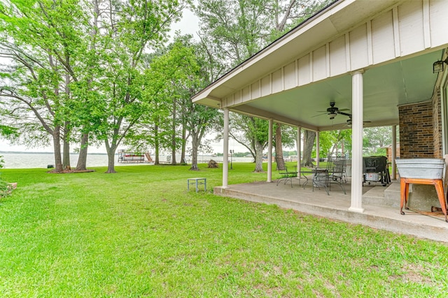 view of yard with a water view, ceiling fan, and a patio area