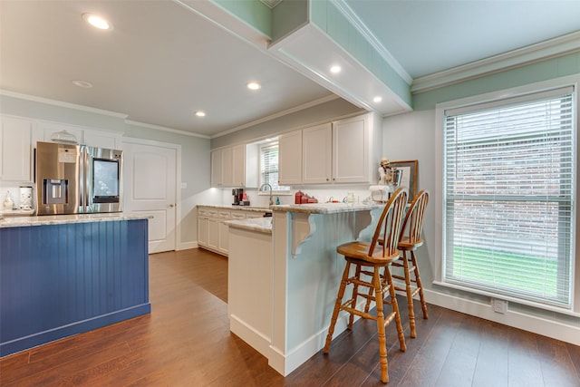 kitchen featuring light stone countertops, dark wood-style floors, stainless steel fridge, ornamental molding, and white cabinetry